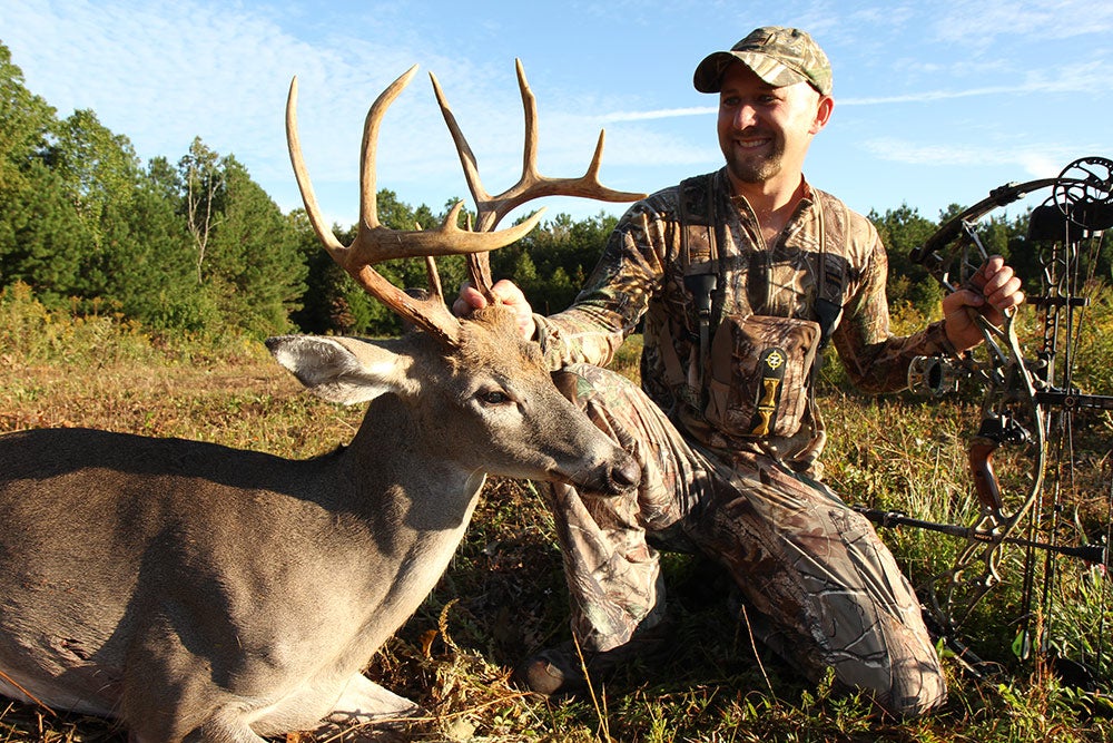 will brantley kneeling next to a 10-point buck