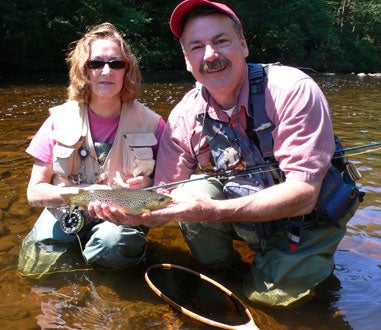 man and woman holding a trout