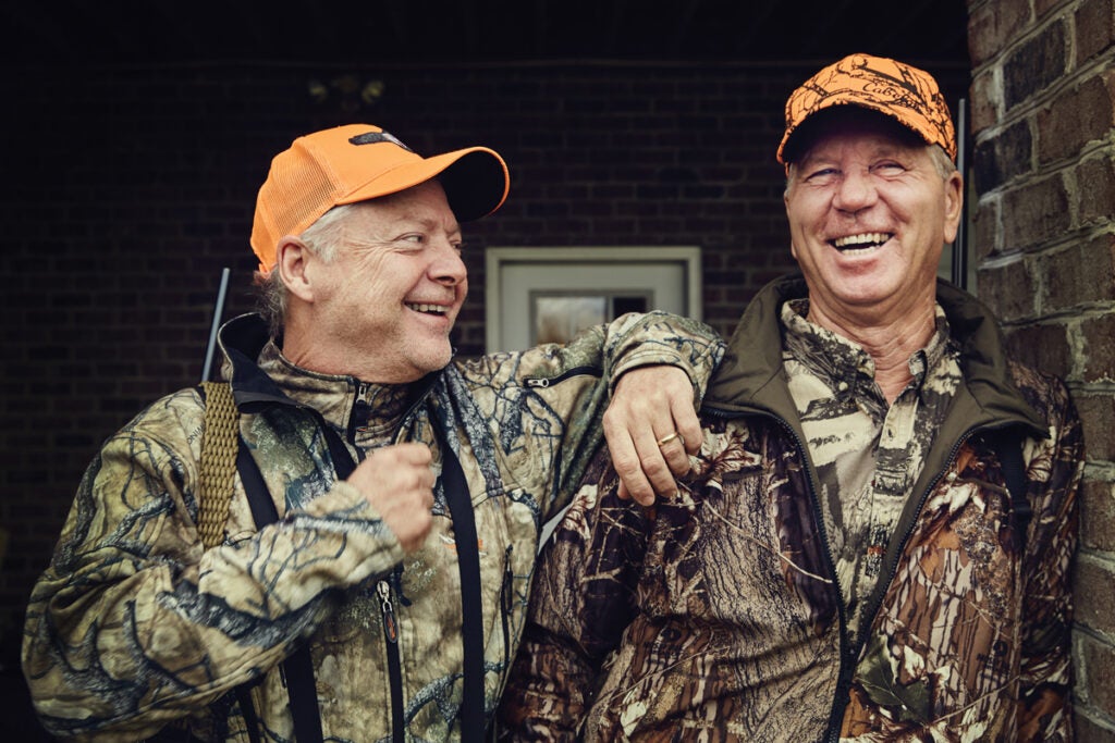 Two hunters smile and stand in the doorway.