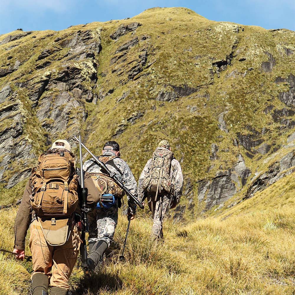 Hunters hiking up a New Zealand hill side