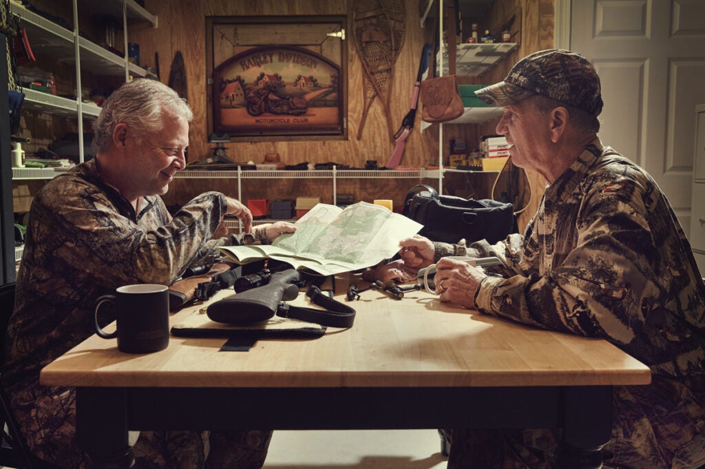 Two hunters planning their hunts while looking at a map.