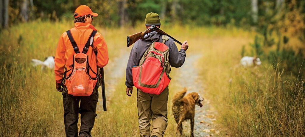 two men and a hunting dog hunting grouse