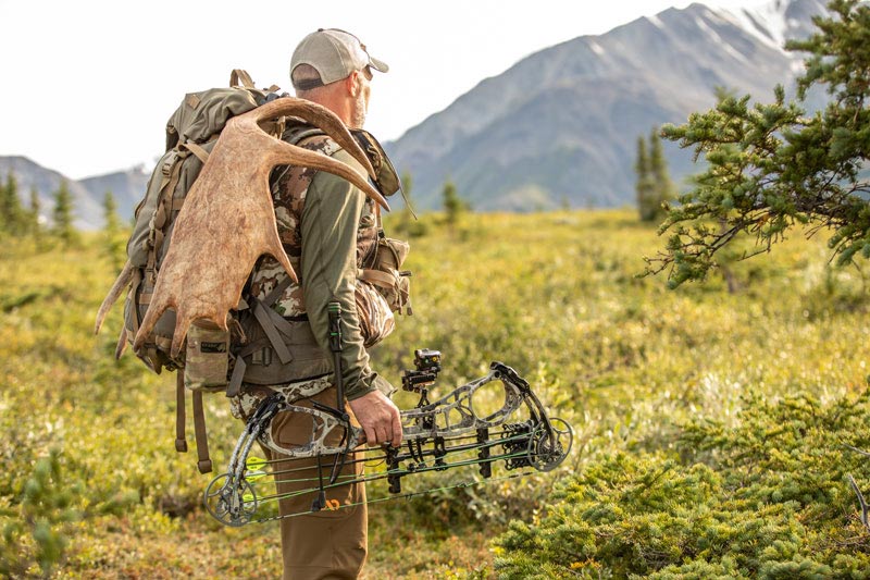 bow hunter with moose antlers on his backpack