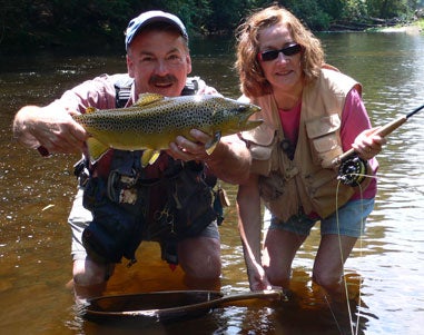 man and woman holding up a trout