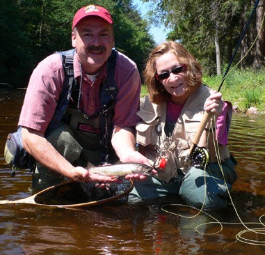 man and woman holding a trout