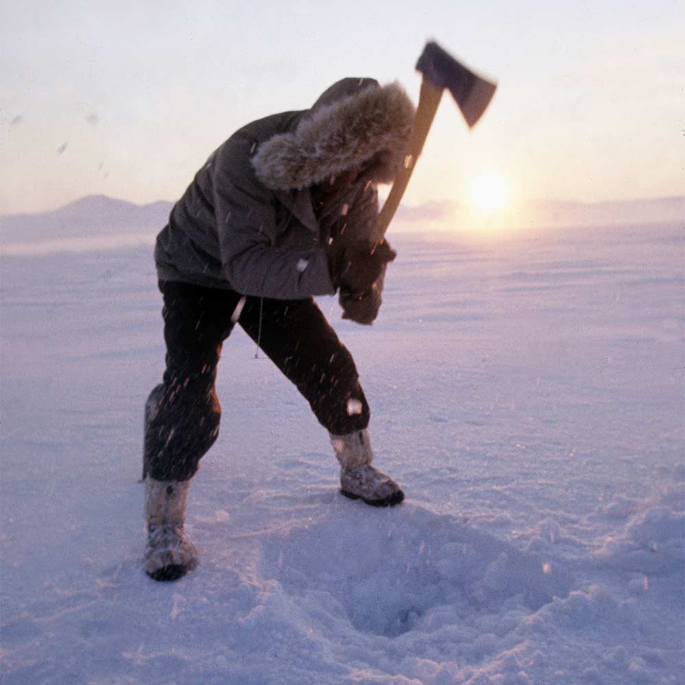 man chopping ice with an axe
