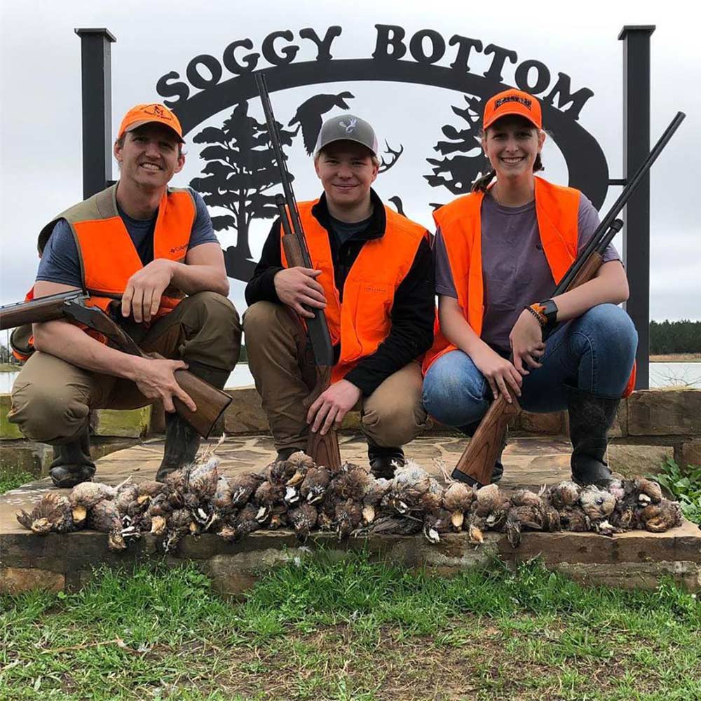 three hunters sitting in front of a sign