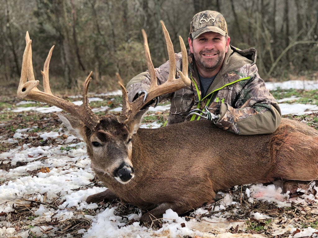 Jason Koger on the snowy ground with massive buck