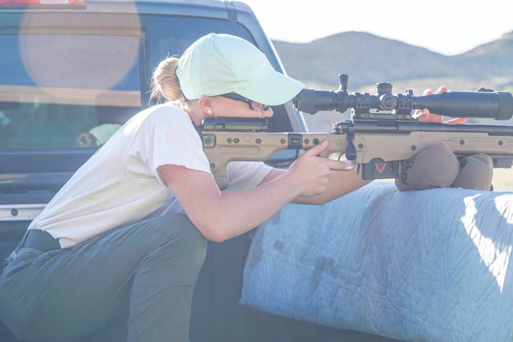woman aiming rifle in truck bed