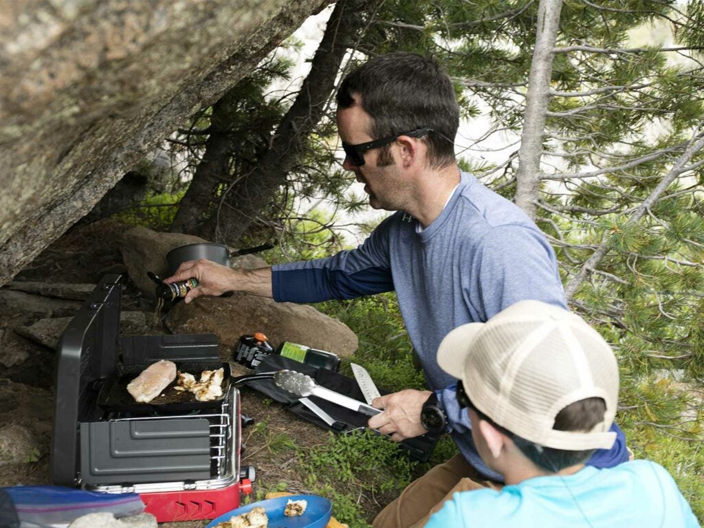 man cooking on outdoor camp grill