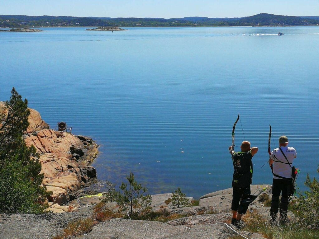 two archers aiming bows above a lake