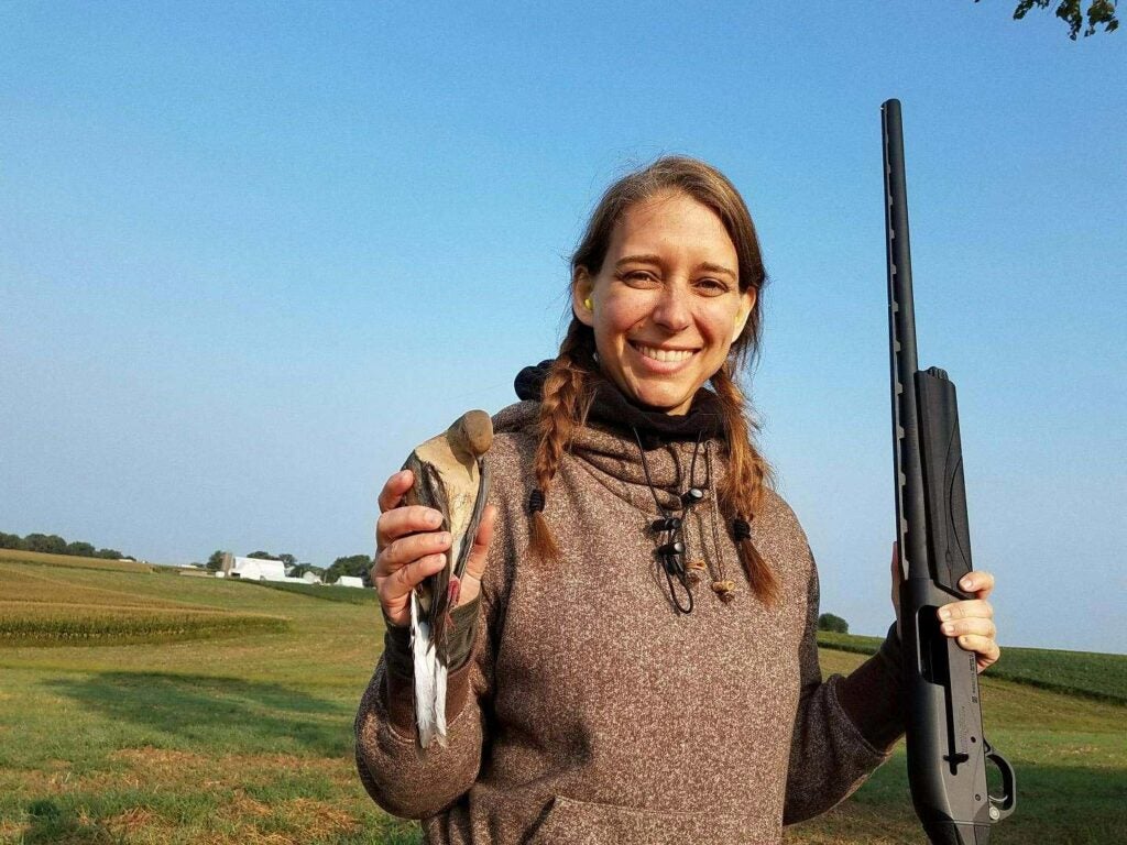 a female hunter holding a dove and a remington shotgun