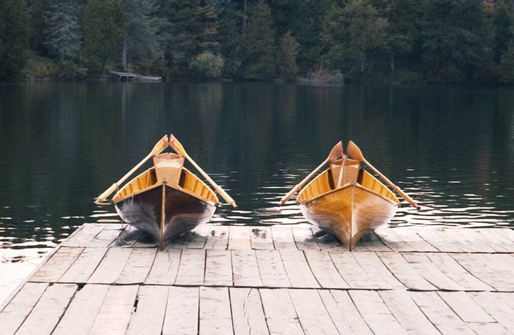 Two Adirondack guide boats sit ready on a dock.