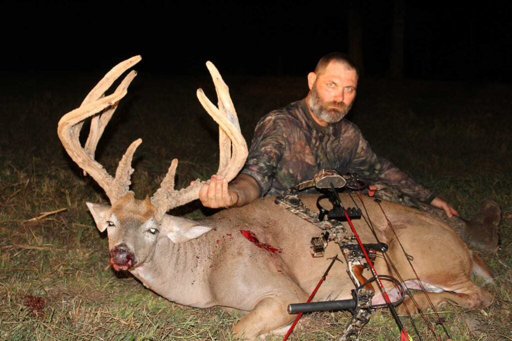 a bowhunter with a large buck and compound bow