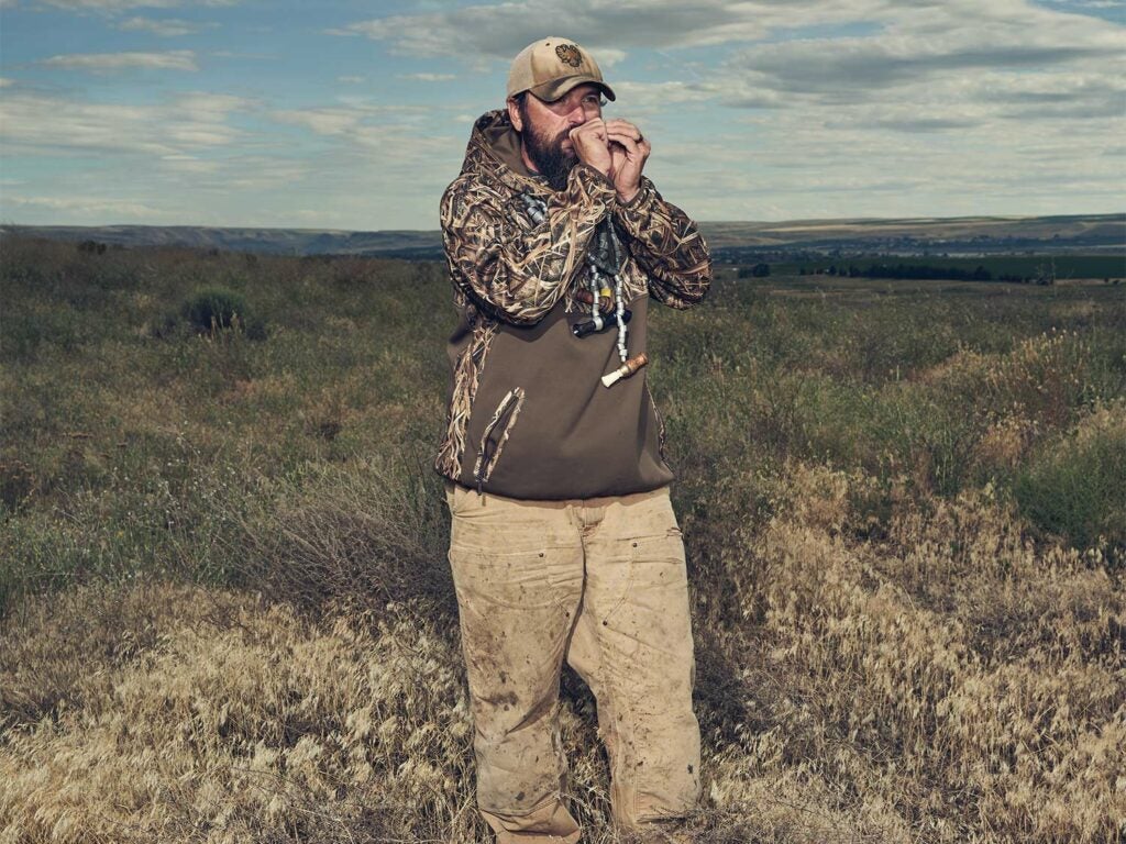 a hunter standing in a field calling ducks