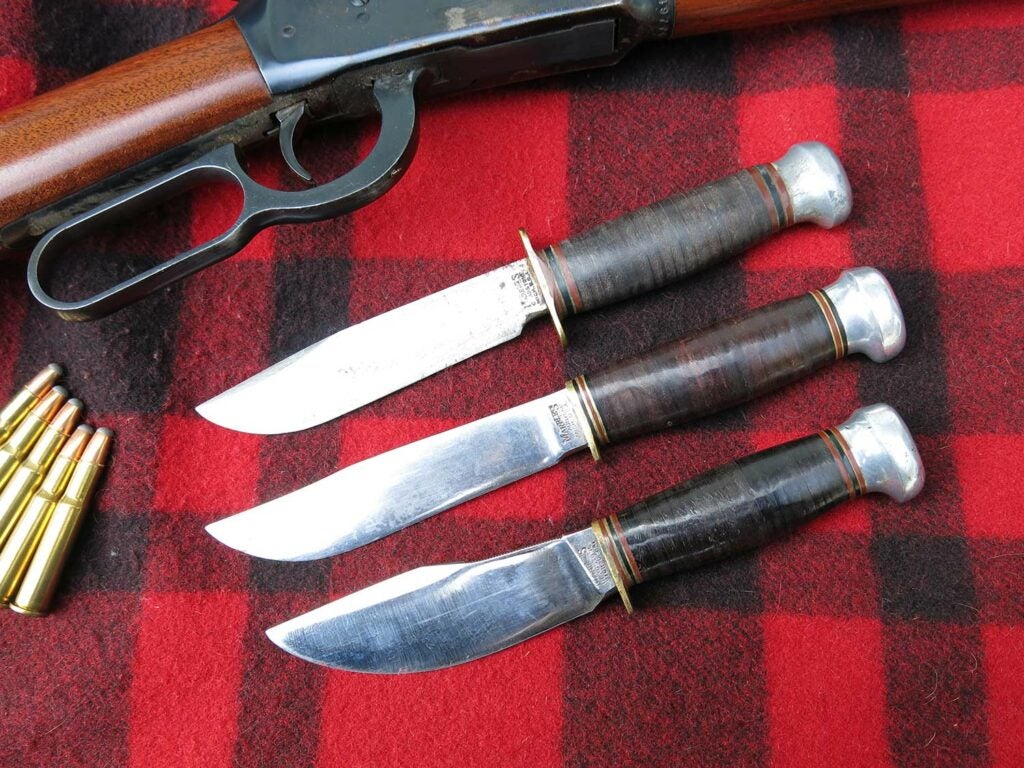 three hunting knives and a lever-action rifle