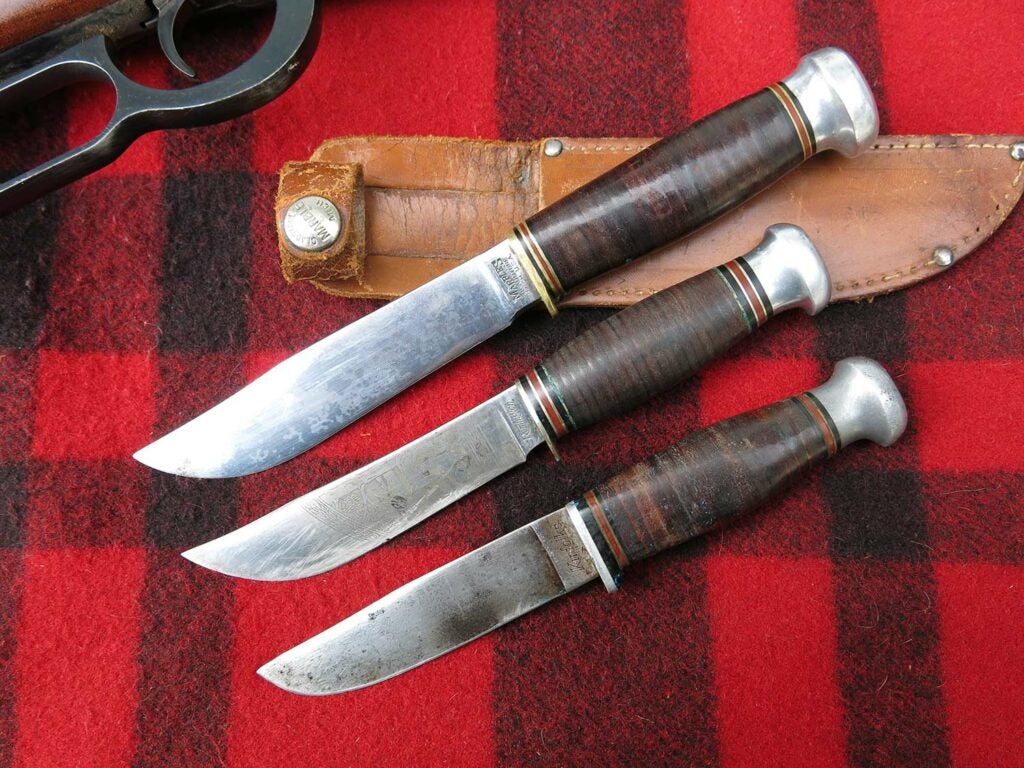 three hunting knives on a plaid background