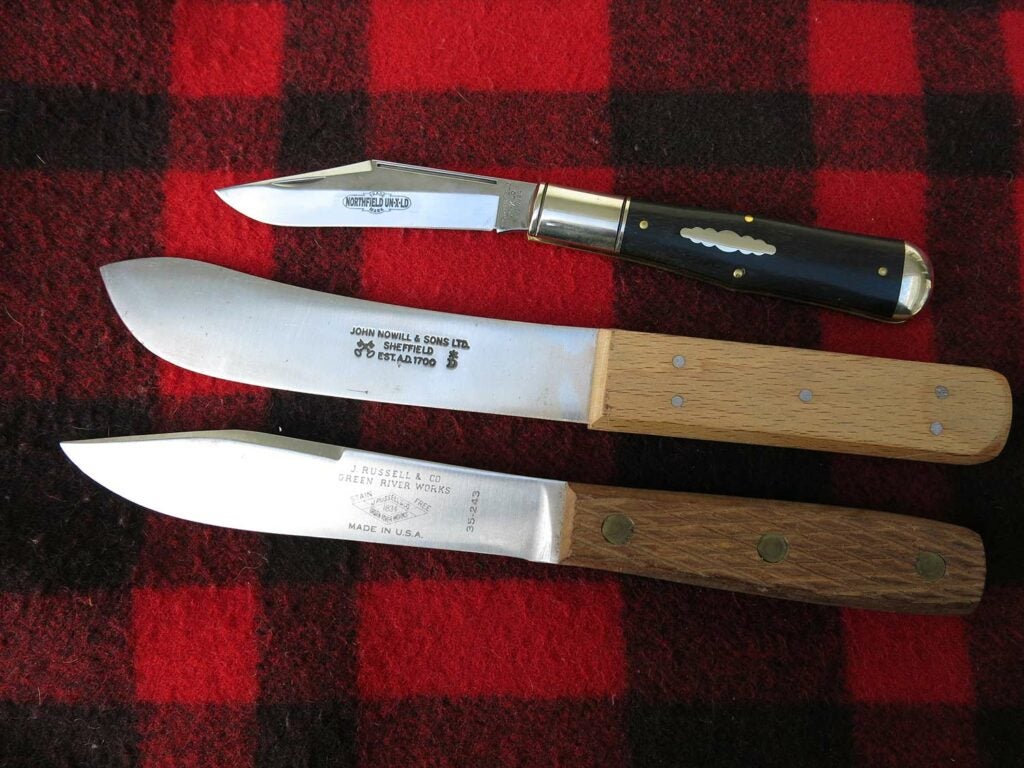 three hunting knives on an antique background