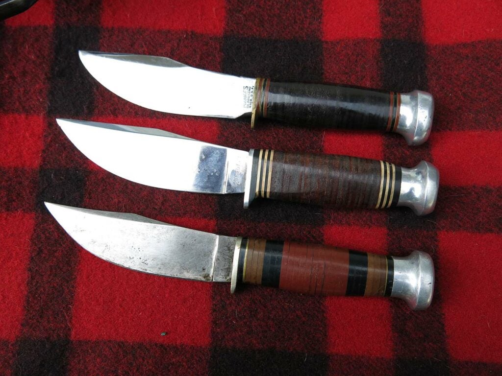 three hunting knives on a plaid background