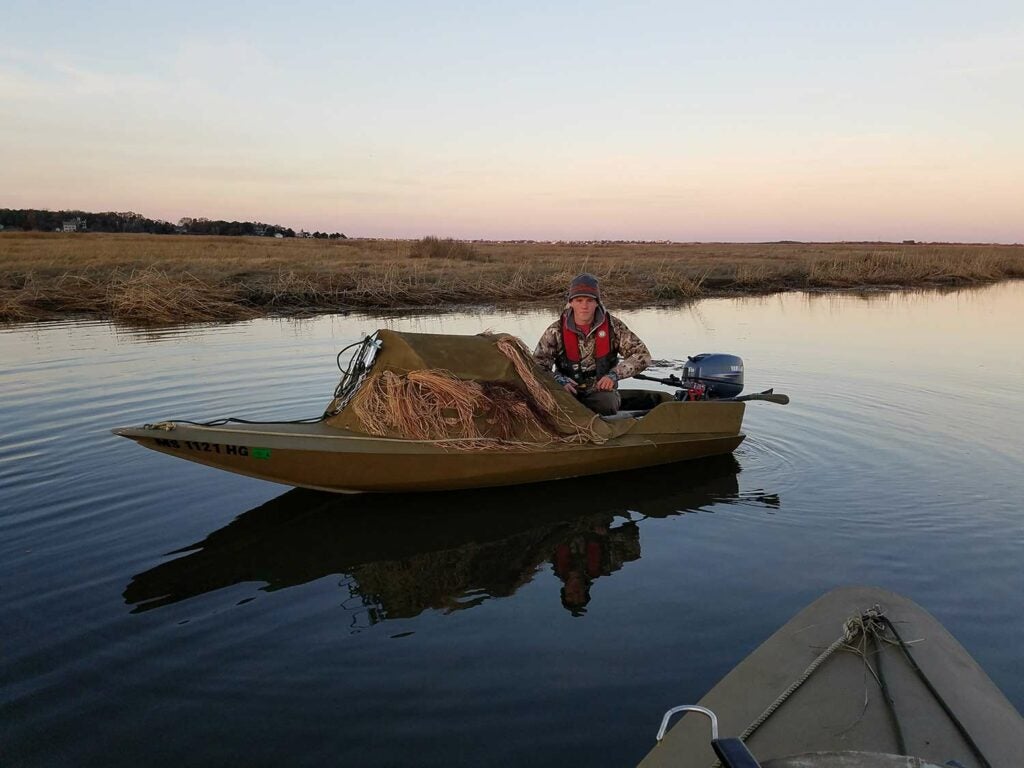 hunter on a boat equipped with duck hunting blind