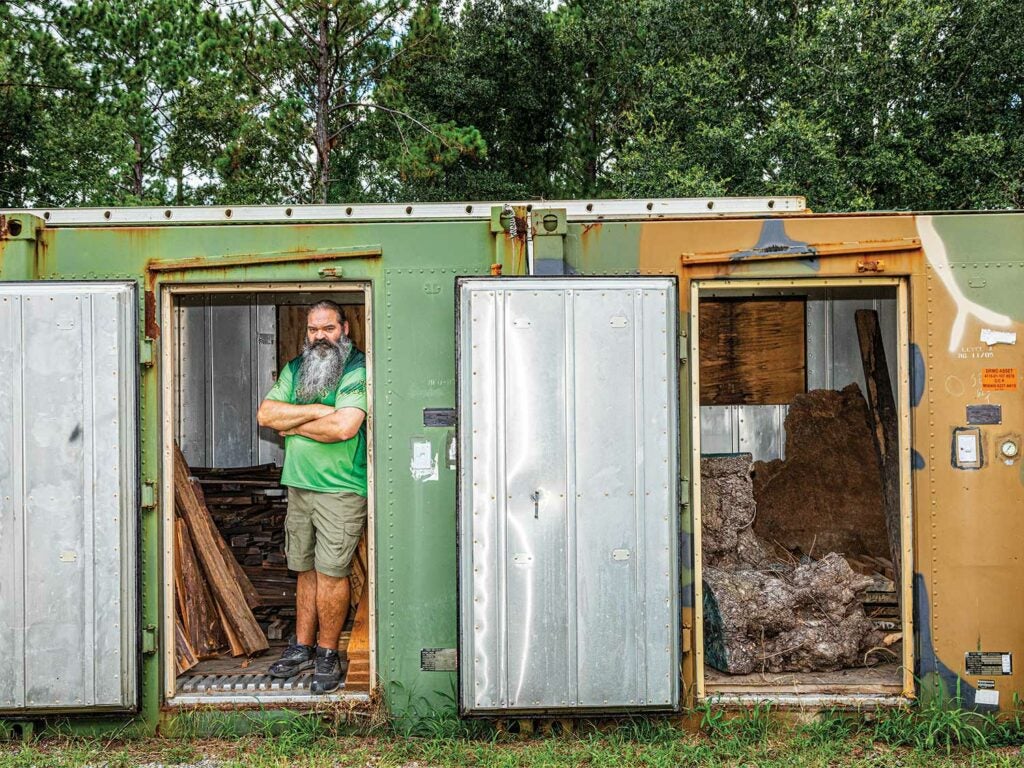 man standing in a trailer that's wood storage