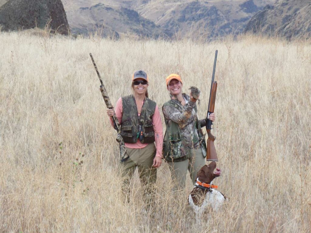two women hunting chukar in a field