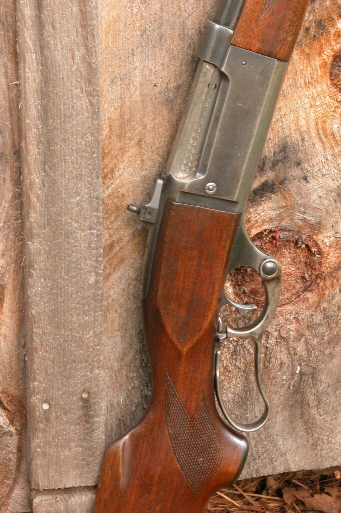 rifle leaning against a slab of wood