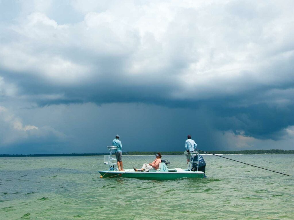 Anglers fishing on a boat with stormy sky.