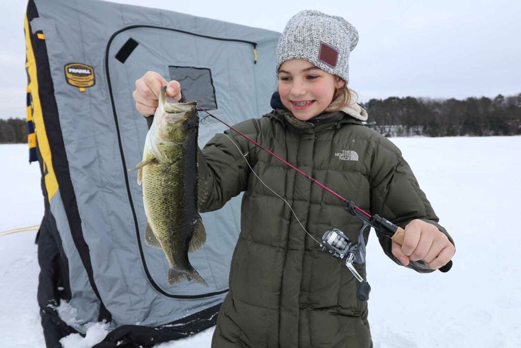Young girl holding up fish in snow