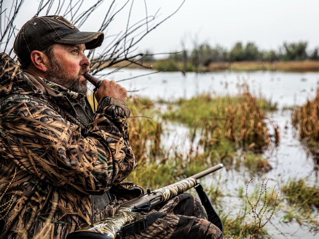 Hunter calling in ducks on a lake.