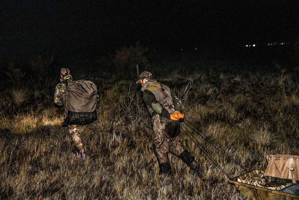 Hunters hauling duck hunting gear at night.