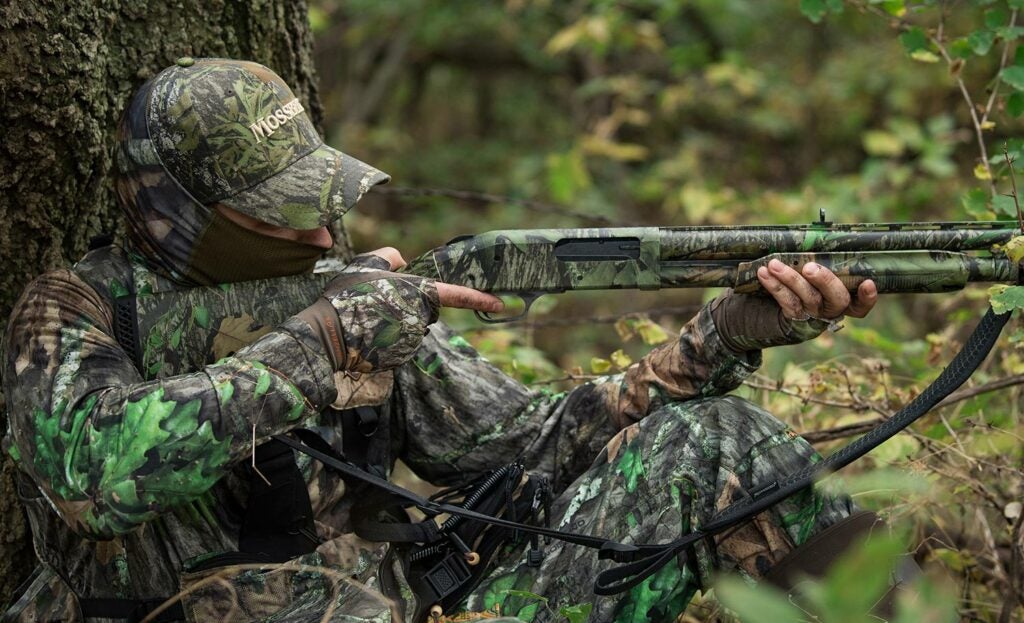 Hunter aiming a Mossberg shotgun.