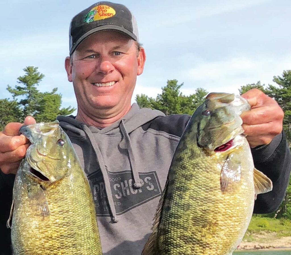Kevin VanDam holding up two spring smallmouth bass.