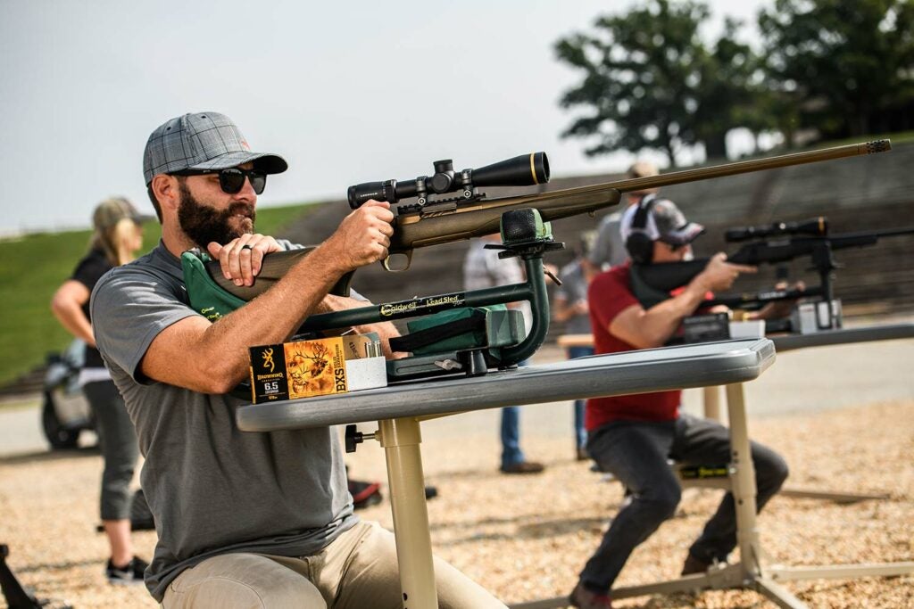 Man aiming a 6.5 Creedmoor rifle at a shooting range.