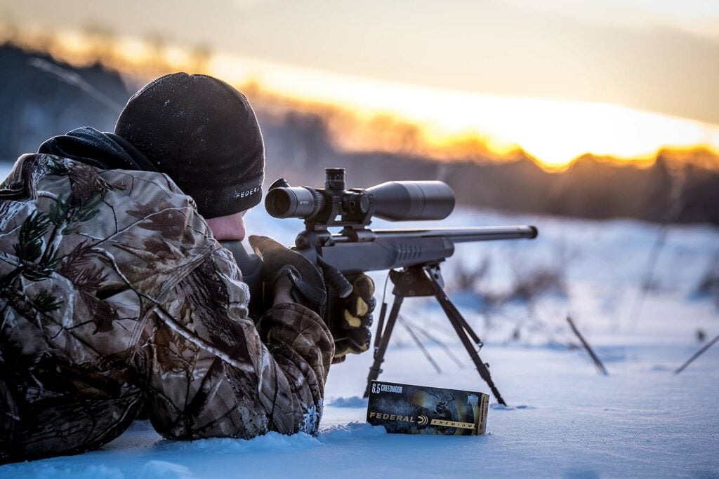 Hunter aiming a 6.5x55 Swede rifle in the snow.