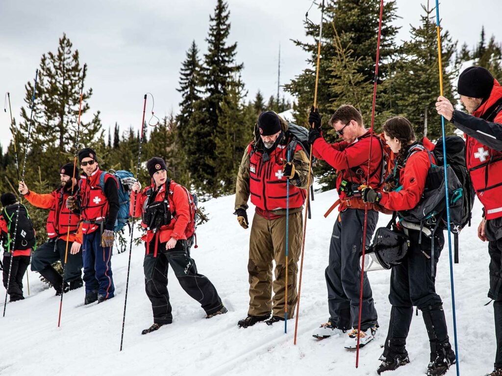 A search and rescue team train with snow poles.