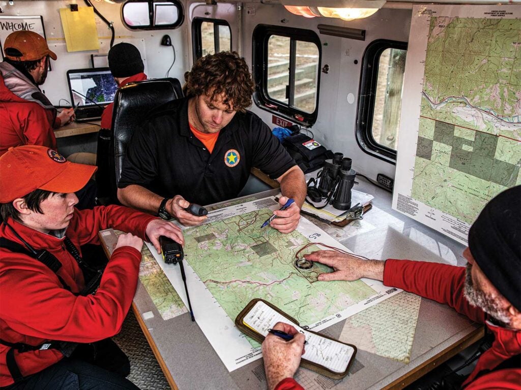 A search and rescue team study a map and coordinates.
