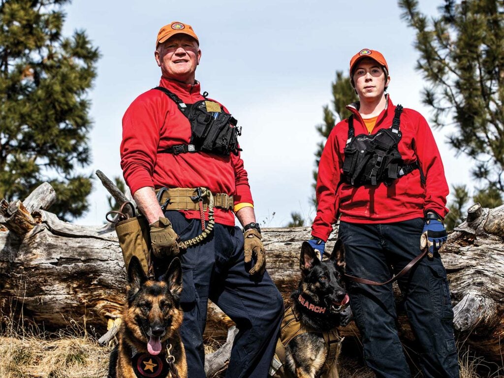 Two search and rescue team members with two German shepherd dogs.
