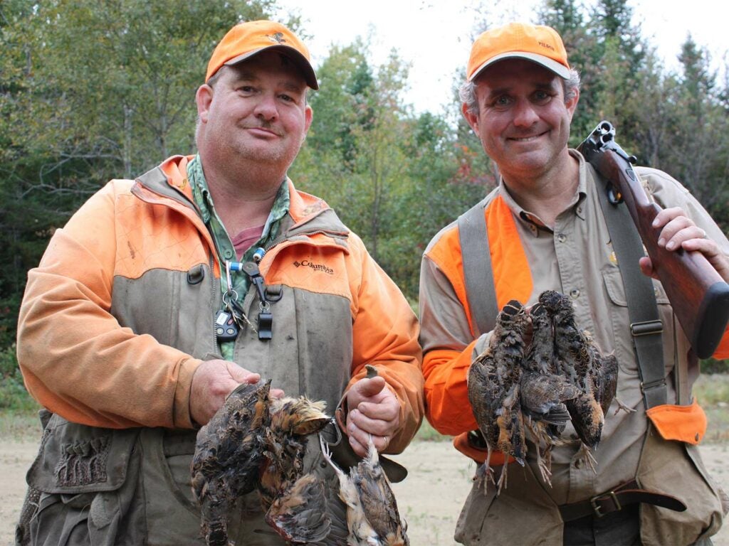 Two hunters holding up birds.