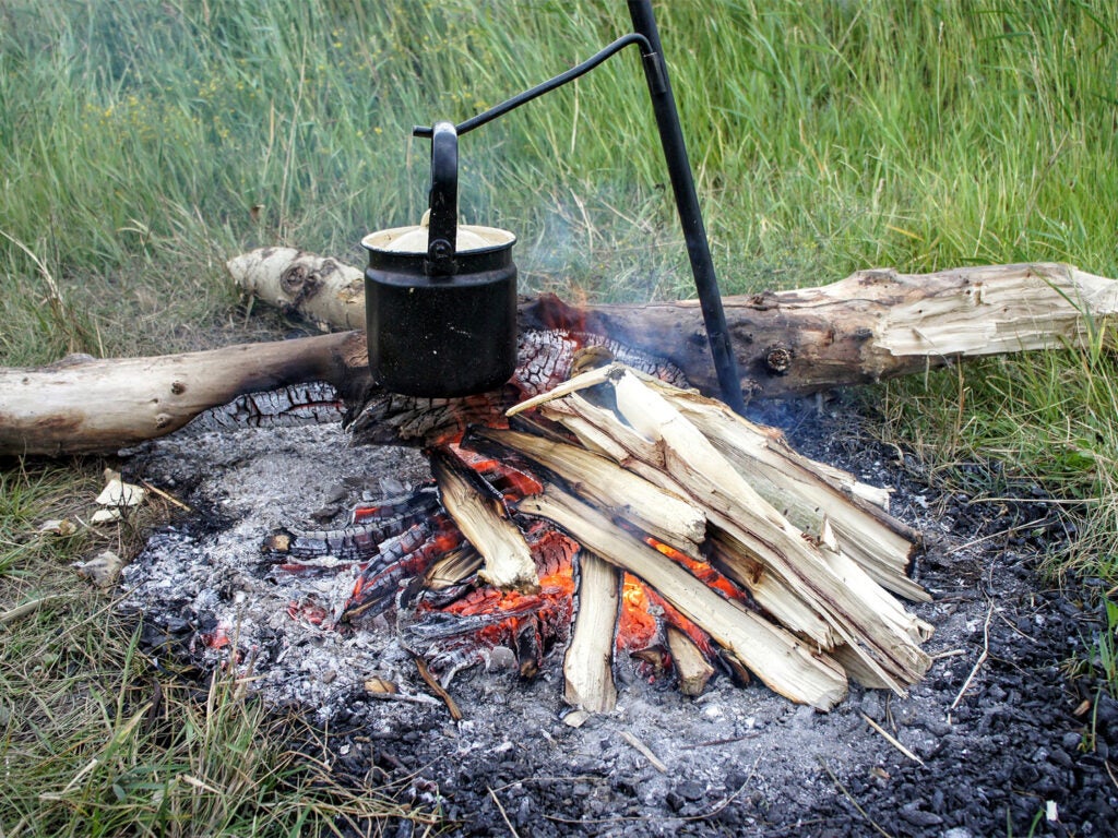 A campfire cookstove over a burning fire.