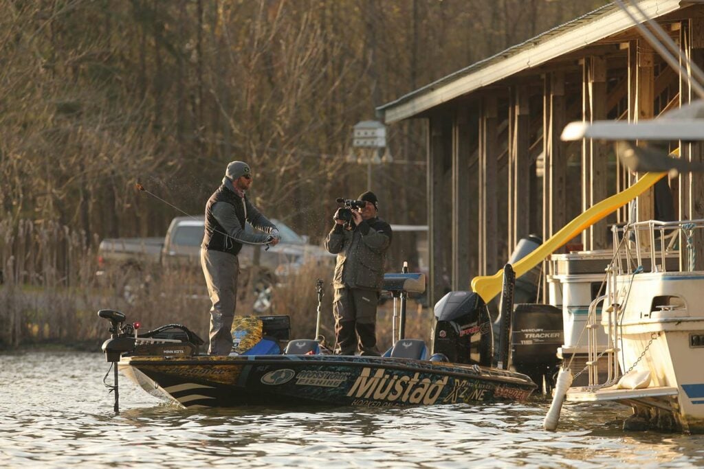 A BASS pro Brandon Lester fishes near a boathouse on a river.