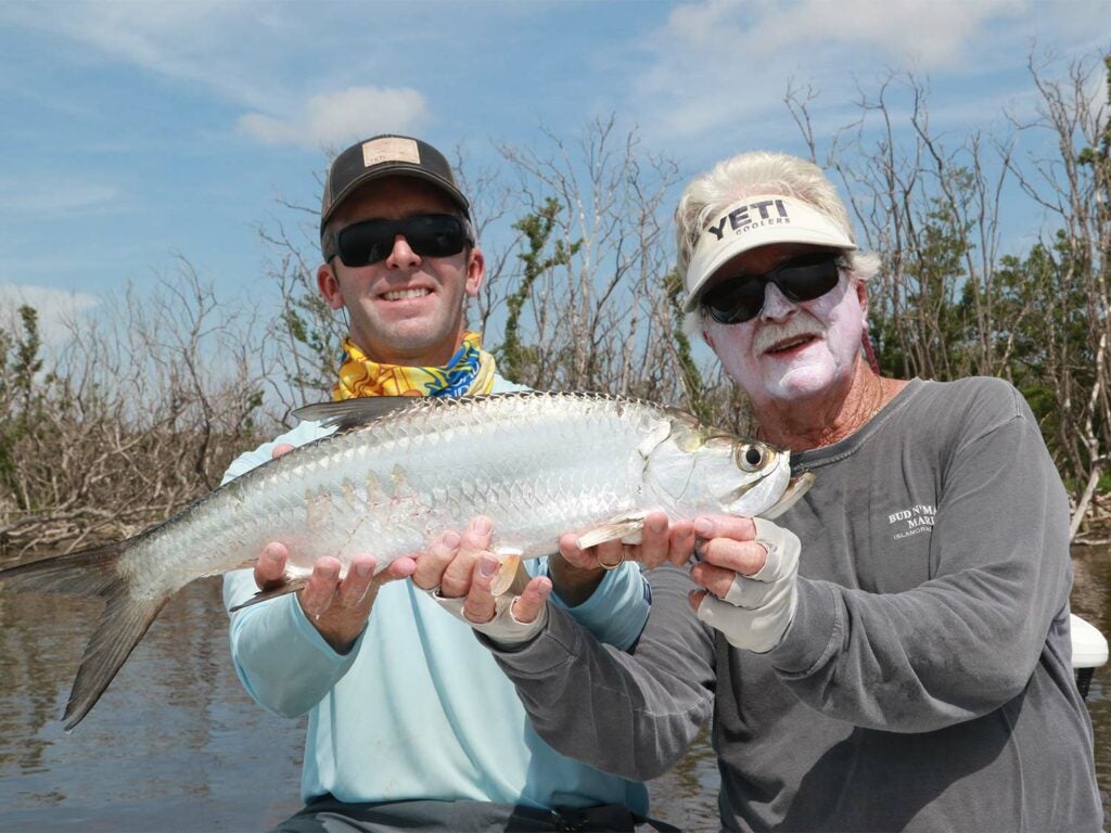 Two anglers holding up a large backcountry tarpon.
