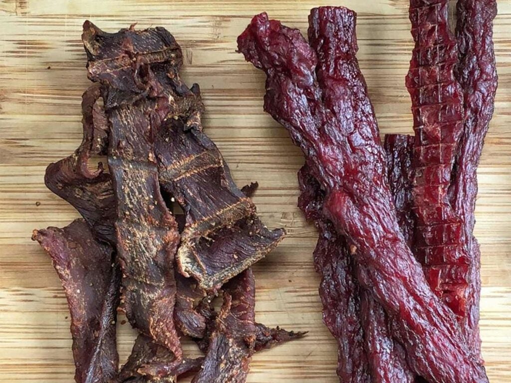 Two types of beef jerky on a cutting board.