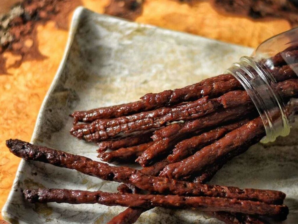 Several beef jerky sticks on a cooking sheet.