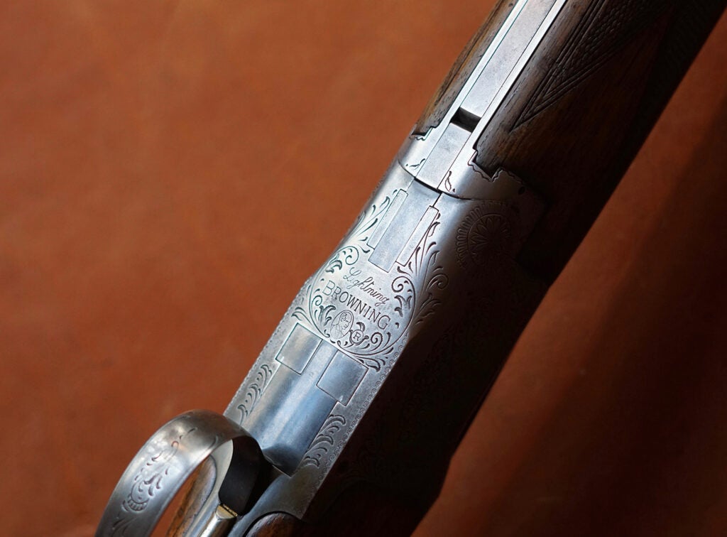 The bottom silver engravings on a Browning shotgun.