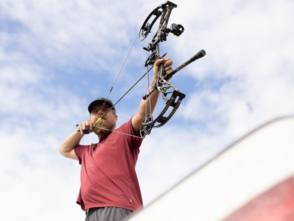 Bowhunter aiming a compound bow and drawing back.