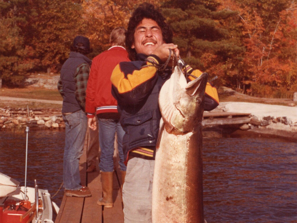 A man holding up a large muskie fish.