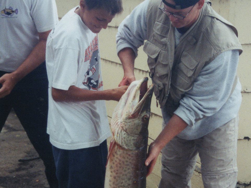 A man and a young boy holding up a large muskie.