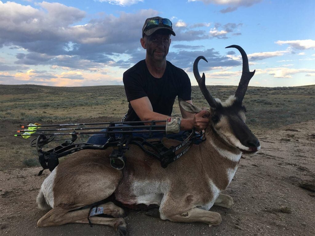 A hunter kneeling beside a pronghorn antelope.