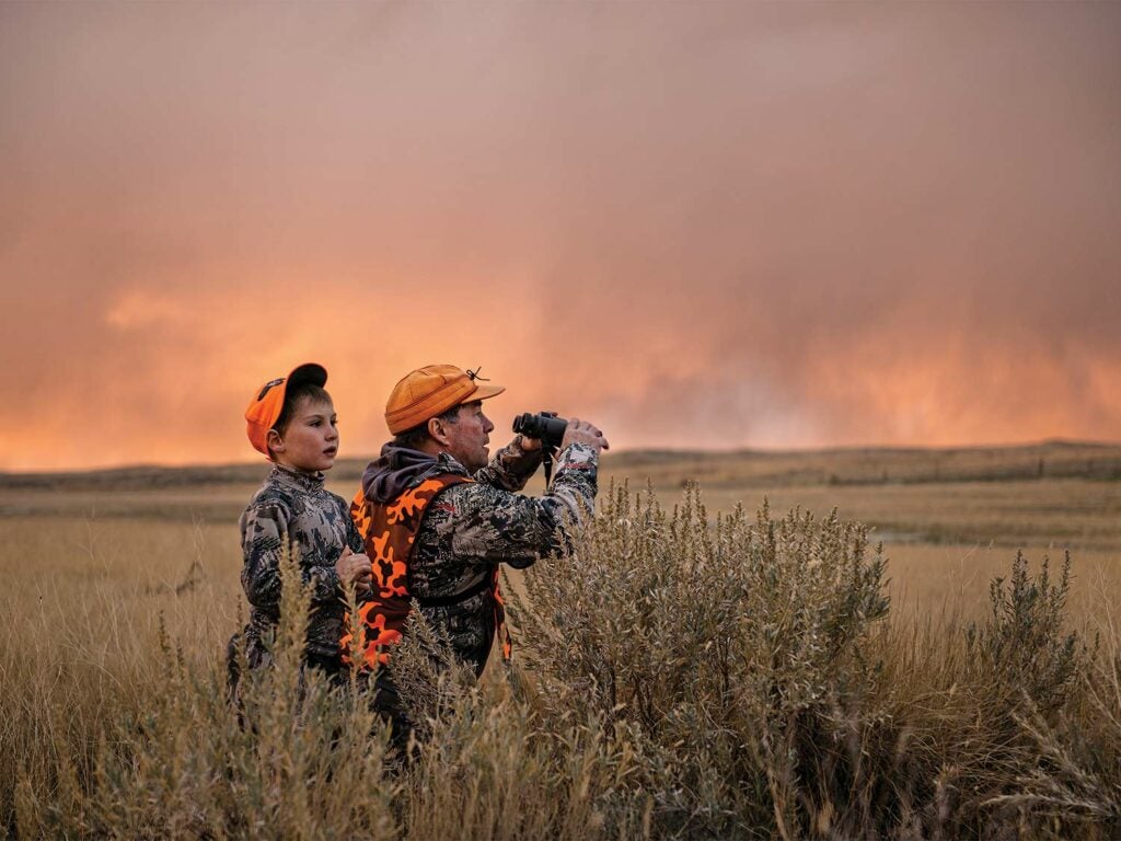 A hunter and small child scouting an open field.
